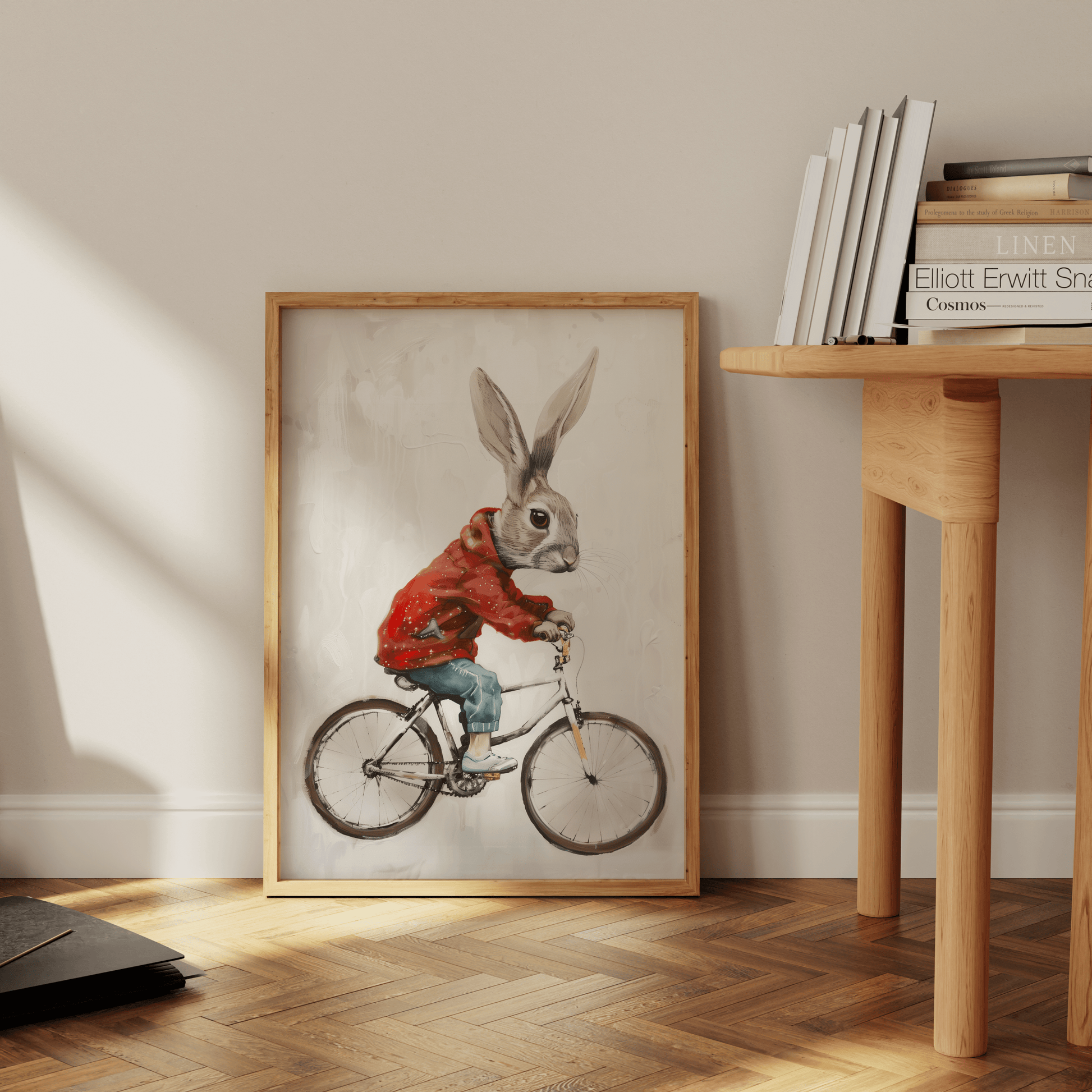 a rabbit riding a bicycle, wearing a red jacket and jeans, in a Paw Prints framed poster leaning against the office floor.